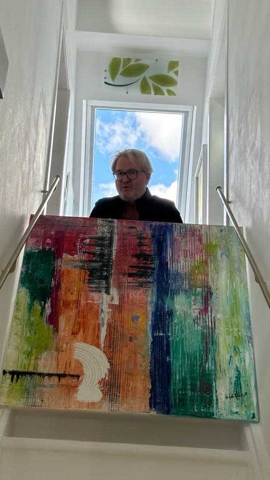 Mitsch Schulz trägt ein großes, farbiges Bild durchs Treppenhaus, Bild 5 von 6