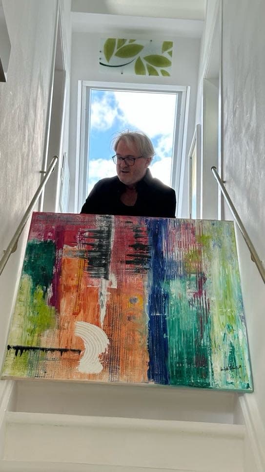 Mitsch Schulz trägt das Farbstreifen-Bild im Treppenhaus