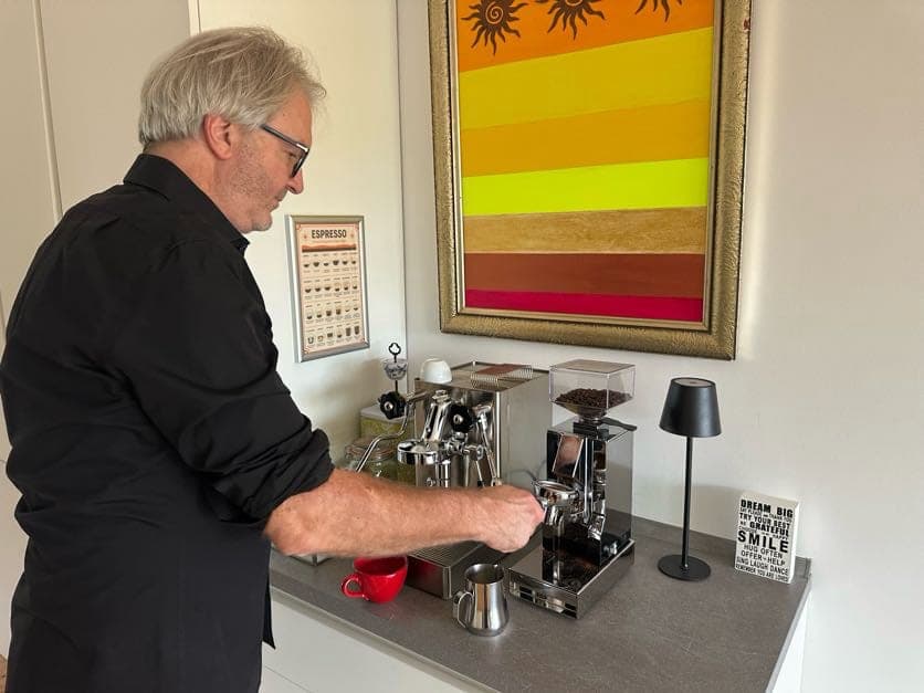 Mitsch Schulz bereitet unter dem Bild einen Espresso zu