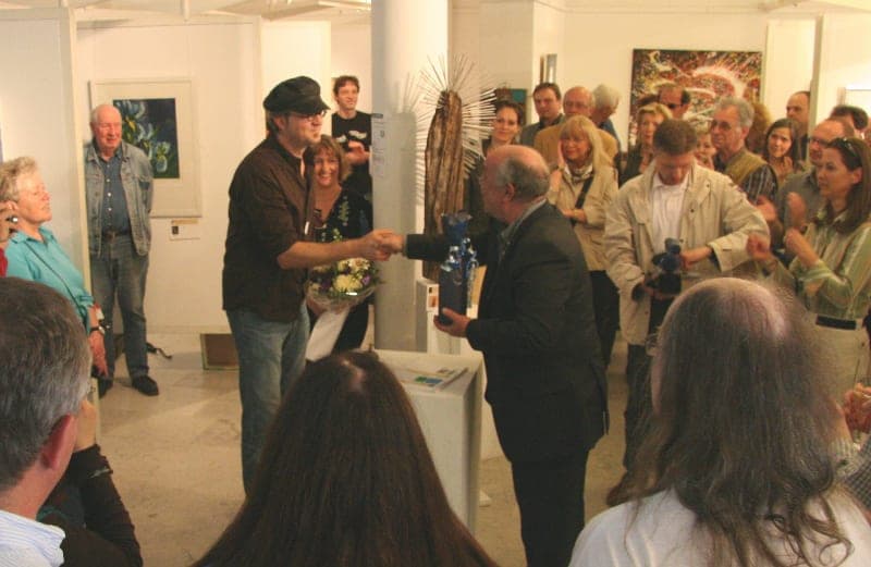 Dicht gedrängte Gäste in einem Ausstellungsraum mit Bildern an den Wänden bei der Aktion Kunst für die Lilien