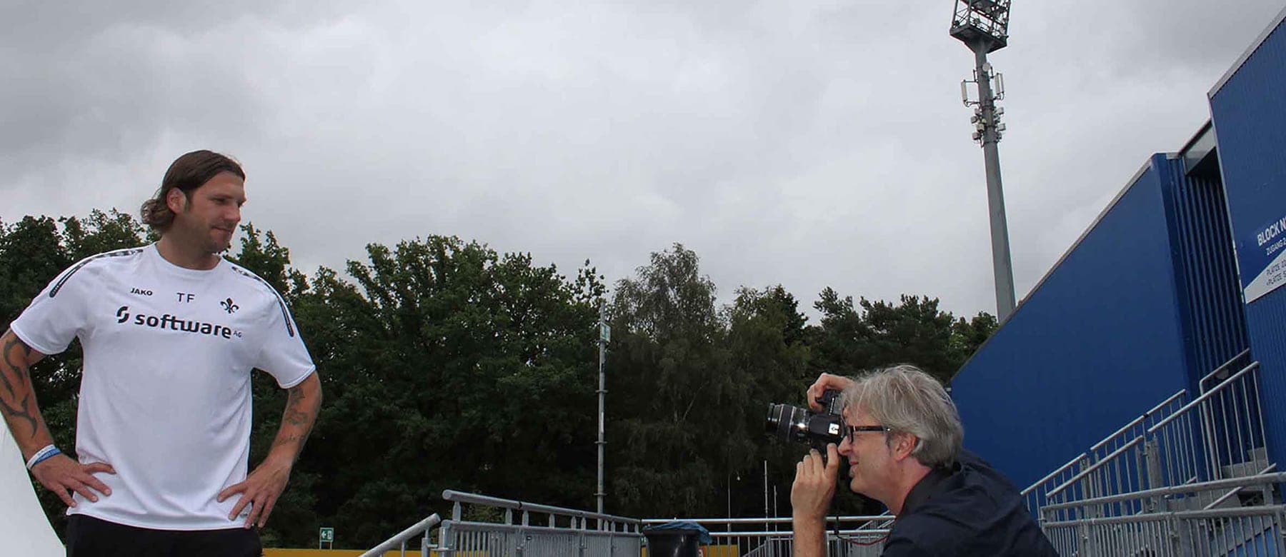 Mitsch Schulz fotografiert am Mediatag einen Trainer im weißen Shirt vor der Tribüne