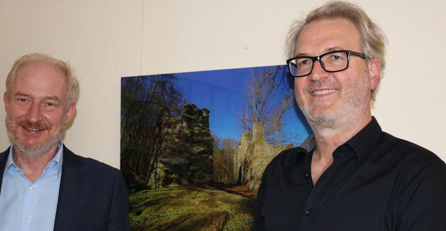 Bürgermeister Eric Engels und Mitsch Schulz vor einem Landschaftsbild im Rathausflur
